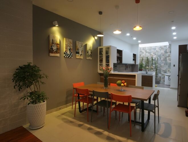 Bếp ăn nằm kế bên hai khoảng thoáng của giếng trời giữa và cuối nhà. Trong lúc chờ bữa cơm, con có thể vui chơi bên hồ cá nhỏ, thật ấn tượng với thiết kế nhà ống này.